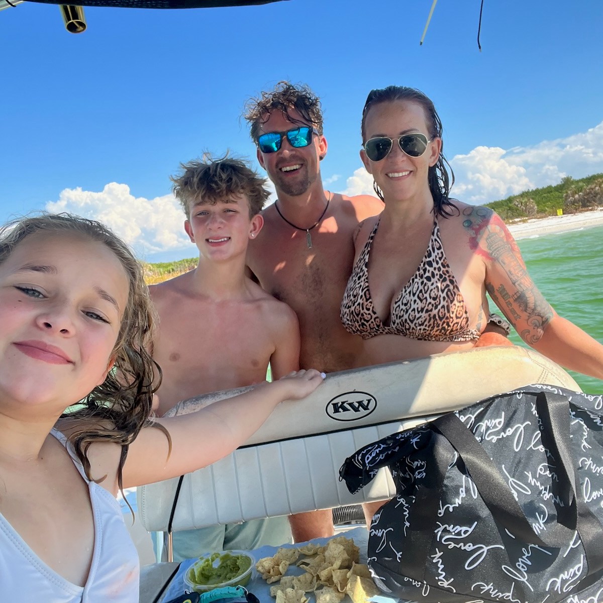 Family on a boat posing for the camera with St Pete Beach in the background
